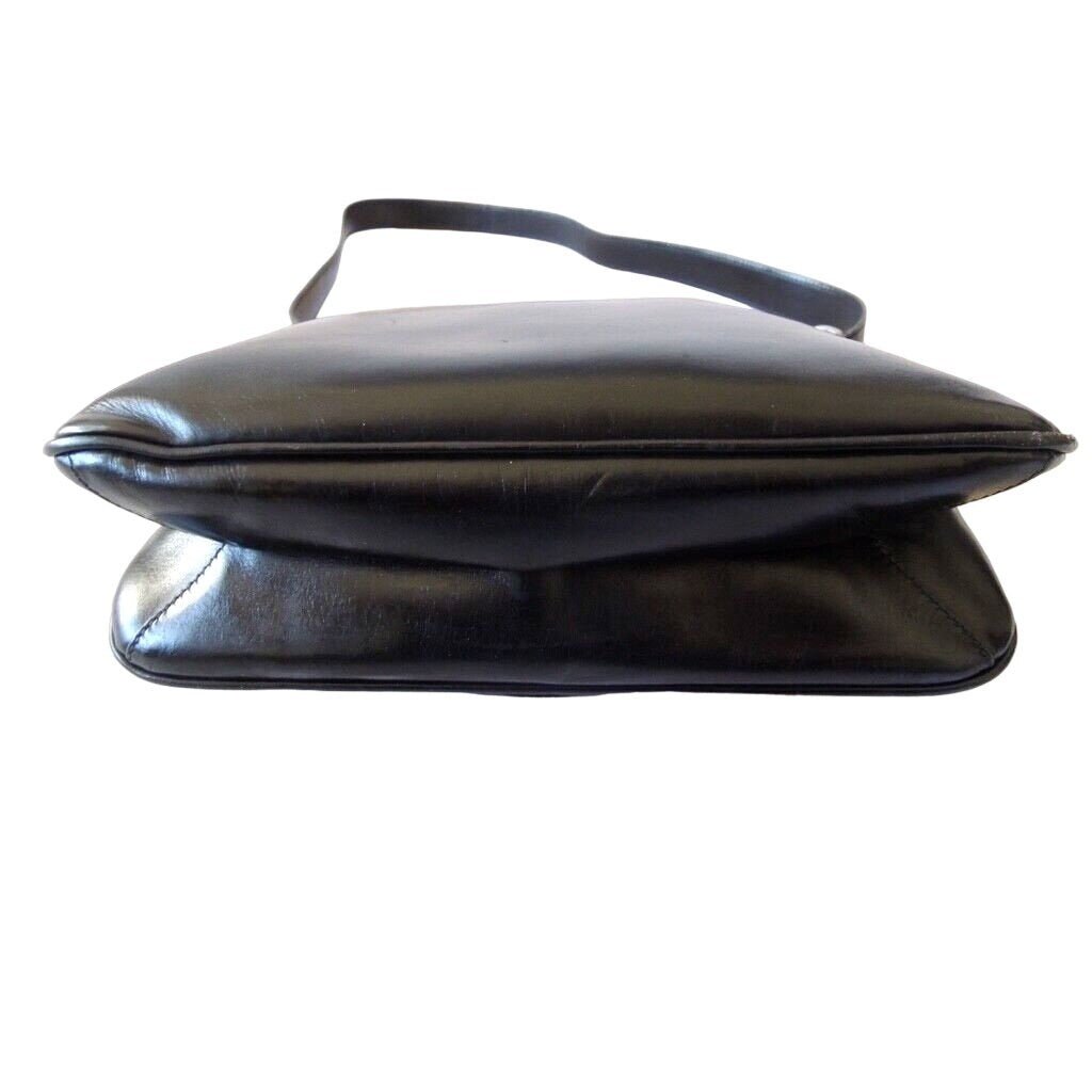 1970s Gucci saddle bag in black leather with muted gold hardware, an expandable bottom, wide shoulder strap, and burgundy leather lining | AlmaBagz